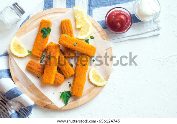 Fried Fish Sticks. Fish Fingers. Fish Sticks with\
lemon and sauces ready to\
eat.