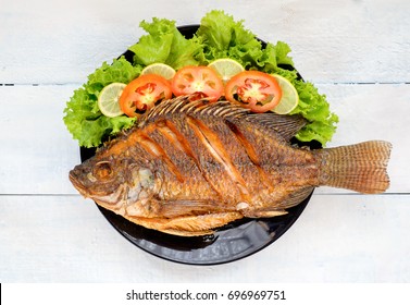 fried fish with vegetable on black dish. top view