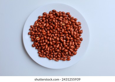 Fried groundnut, Goober or Monkey Nut, or Arachis hypogaea. On a white plate, isolated on white background. Flat lay or top view