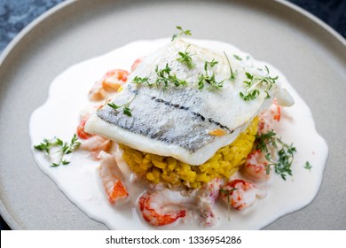 Fried Haddock Filet With Saffron Rice And Shell Prawns In Crab Sauce As Closeup On A Modern Design Plate