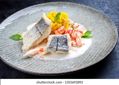 Fried Haddock Filet With Saffron Rice And Shell Prawns In Crab Sauce As Closeup On A Modern Design Plate 