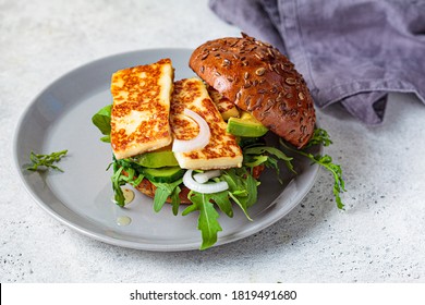 Fried halloumi burger with avocado wedges and arugula. Vegetarian food concept.