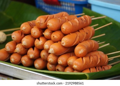 Fried hot dogs skewers, stacked for sale.