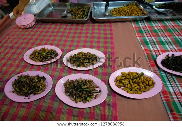 Fried insects,\
grasshoppers and silkworms were divided in the pink dishes for sale\
at the street market.