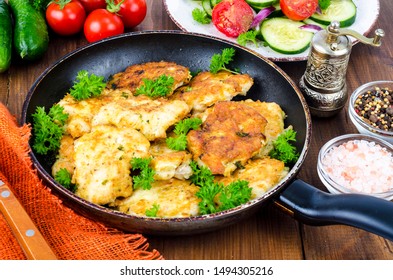 Fried meat pancakes in pan, vegetables, wooden background. Studio Photo