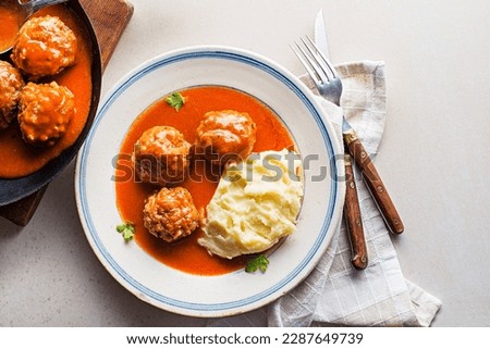 Fried meatballs braised in tomato sauce served with mashed potatoes on white table. Eating Beef roasted meatballs in tomato sauce.