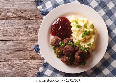 fried meatballs, lingonberry sauce with potato garnish on a plate. horizontal view from above
