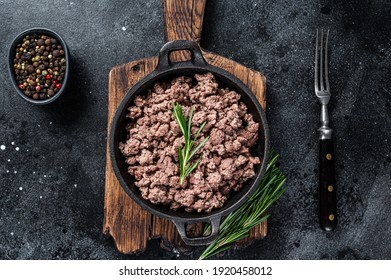 Carne de carne de ternera frita en una sartén para cocinar pasta. Fondo negro. Vista superior
