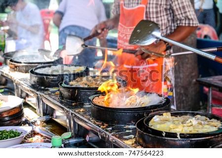 Fried mussel pancakes with egg are cooking on the pan with smoke and fire