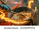 fried noodles cook in pan with big fire flame is hong kong style. Pad Thai favorite and famous Asian Thai street fast food in hot pan, Pad Thai is fried rice noodle dish a street food Thailand