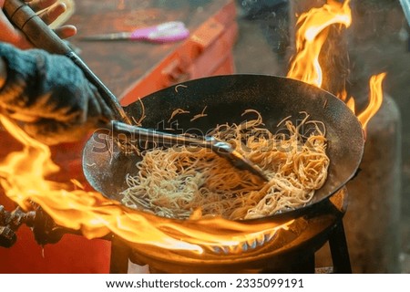 fried noodles cook in pan with big fire flame is hong kong style. Pad Thai favorite and famous Asian Thai street fast food in hot pan, Pad Thai is fried rice noodle dish a street food Thailand