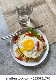 Fried Noodles On White Round Plate With Sunny Side Up Egg And Chilis With Chopstick