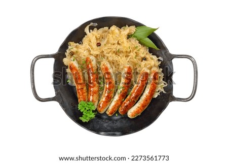 Fried Nuremberg sausages with sauerkraut served in an iron frying pan on white background