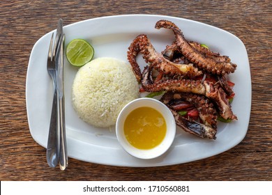 Fried octopus tentacles with white rice on a plate in restaurant, island Zanzibar, Tanzania, Africa, close up.