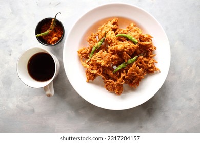 Fried onion pakode or Pyaj ke Pakore also known as Crispy Kanda bhaji, Bhajji, bujji. favorite Indian Tea-Time snack during the monsoon. served with fried green chili and red garlic chutney.copy space - Shutterstock ID 2317204157