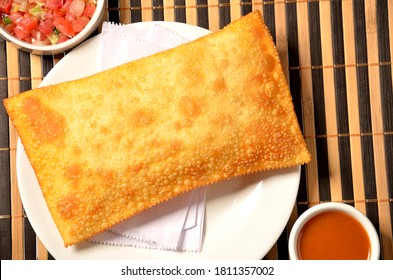 fried pastry on plate served with sauces on bamboo mat