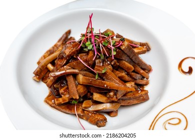 Fried Pieces Of Pork In Sauce Decorated With Microgreens. Marinated Pig Ears.