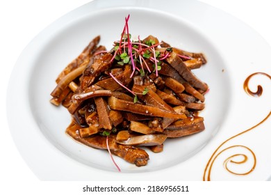 Fried Pieces Of Pork In Sauce Decorated With Microgreens. Marinated Pig Ears.