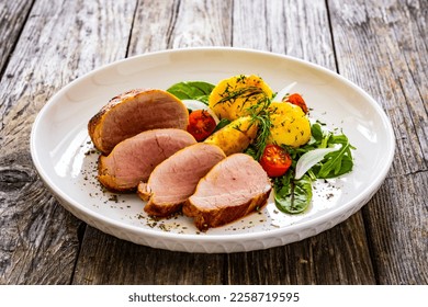 Fried pork loin with fried potatoes and vegetables on wooden table  - Powered by Shutterstock