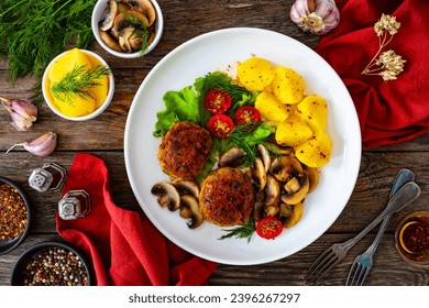 Fried pork meatballs with boiled potatoes and fried mushrooms on wooden table  - Shutterstock ID 2396267297