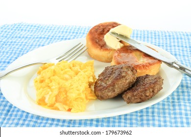 Fried Pork Sausage Patties On White Plate With Eggs Scrambled With Cheese And Large Dollop Of Butter Melting On Biscuits.