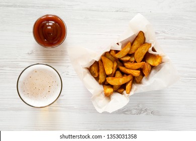 Fried Potato Wedges In Paper Box, Barbecue Sauce And Glass Of Cold Beer On A White Wooden Surface, Top View. Flat Lay, Overhead.