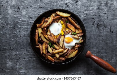 Fried potatoes with meat, ham and eggs in a pan close-up. horizontal