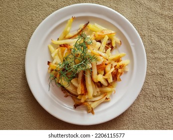 Fried Potatoes With Onion And Green Dill Sprig On A White Porcelain Plate.