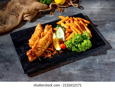 Fried Red Tilapia Fish With Salad, Lime And Fries In A Dish Side View On Dark Background