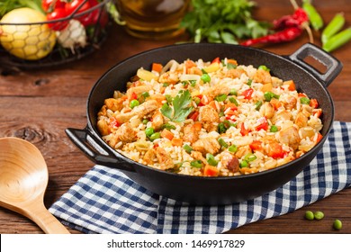 Fried rice with chicken. Prepared and served in a wok. Natural wood in the background. Front view.