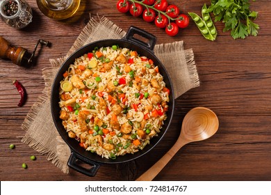 Fried rice with chicken. Prepared and served in a wok. Natural wood in the background. Top view.