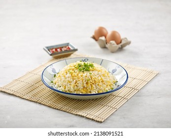 Fried Rice with Shredded Egg with sauce isolated on wooden mat side view on grey background a morning meal