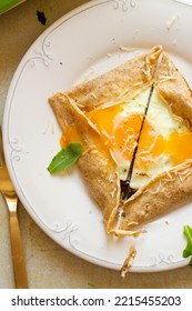 Fried Runny Egg Yolk In A Pancake Sliced In Half On A White Plate Served For Breakfast