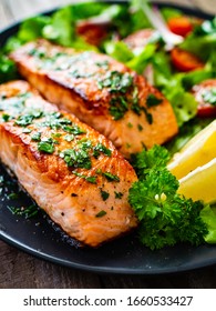 Fried salmon steaks with vegetables on wooden table