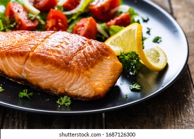 Fried salmon steaks with vegetables on wooden table