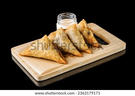  Fried samosas with fresh dipping sauce. Dough patty filled with various fillings (meat, vegetable, cheese,rice). wrapped in triangular and deep fried. Popular snack in the Middle East and South Asia