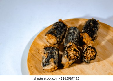 Fried samyang with seaweed skin rolls arranged on a wooden cutting board with a plain white background