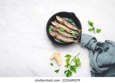 Fried sardines on the small  а frying pan with  parsley and lemon. White background, top view, copy space - Powered by Shutterstock