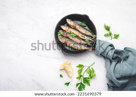 Fried sardines on the small  а frying pan with  parsley and lemon. White background, top view, copy space Сток-фото © 