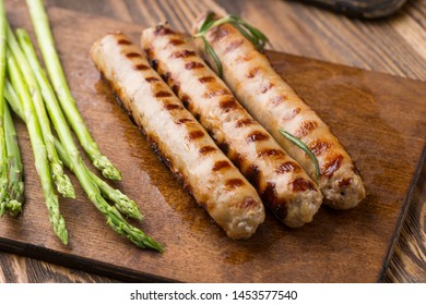 Fried sausages with asparagus.  on a wooden serving Board. Great beer snack on a dark background. Top view with copy space - Shutterstock ID 1453577540