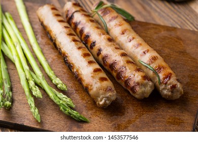 Fried sausages with asparagus.  on a wooden serving Board. Great beer snack on a dark background. Top view with copy space - Shutterstock ID 1453577546