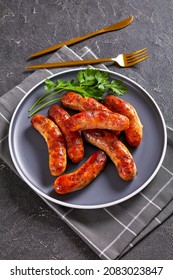 fried sausages, bangers on a plate on a concrete table, vertical view from above