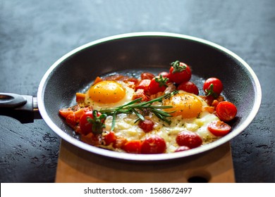 
Fried scrambled eggs in a pan on a black background with cherry tomatoes, cheese and rosemary. Fried egg with a liquid yolk is crushed by herbs. Eggs in a teflon pan. Quick breakfast for every day - Powered by Shutterstock