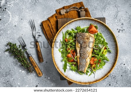 Fried sea bass fillet with vegetable salad, Dicentrarchus fish. Gray background. Top view.