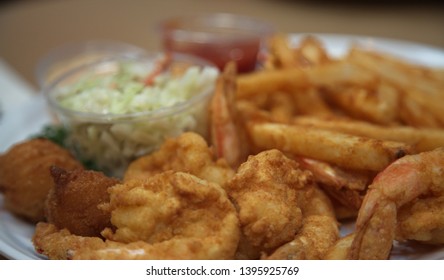 A Fried Shrimp Dinner With French Fries, Cole Slaw And Hush Puppies