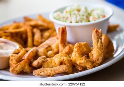 A Fried Shrimp Dinner With French Fries, Coleslaw And Sauce