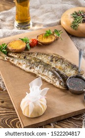 Fried Smelt Fish, Lemon Slice And Potato Wedges On Paper And Glass Of Beer On Wooden Table Side View