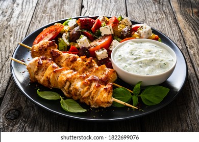 Fried souvlaki, greek salad and tzatziki on wooden table