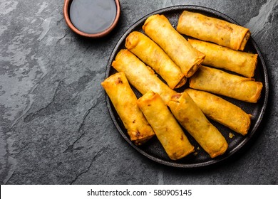 Fried spring rolls on black iron plate on grey stone slate background. Top view, copy space