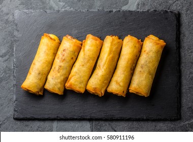 Fried spring rolls on black slate plate on grey stone slate background. Top view
